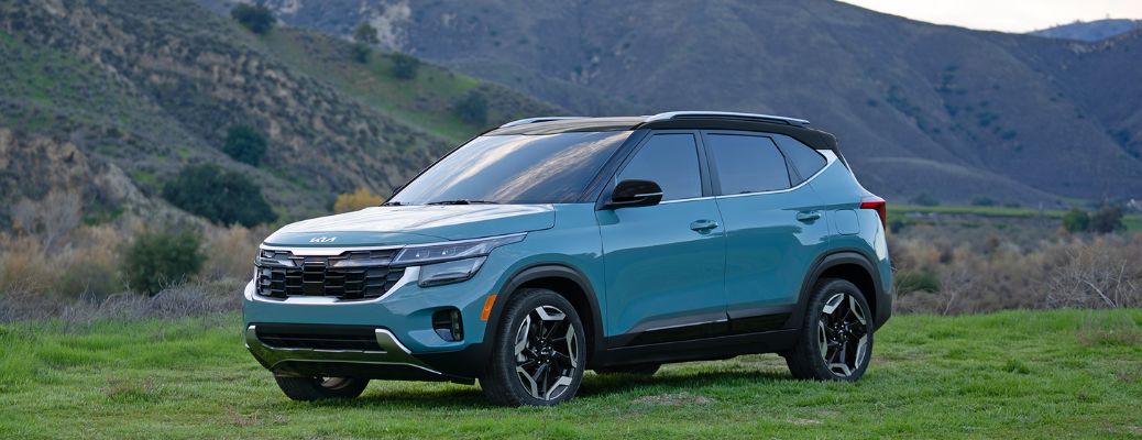 2024 Kia Seltos Parked Off-Road on a Grassy Field Near The Hills Three-Quarter View