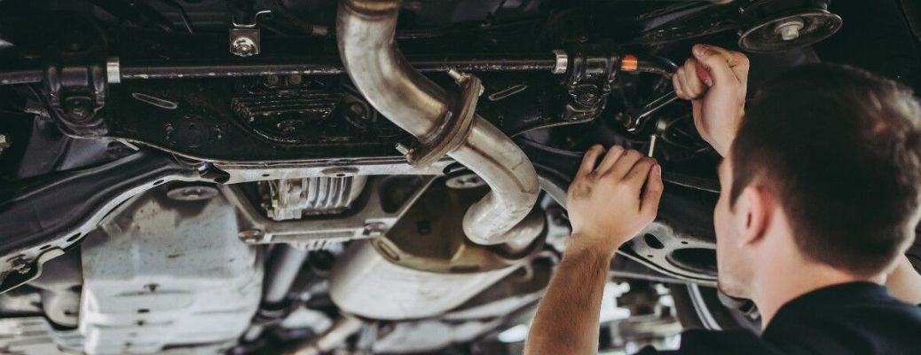 Mechanic working on muffler and exhaust pipe