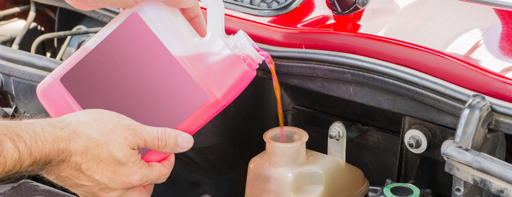 A mechanic filling new and fresh coolant in a vehicle