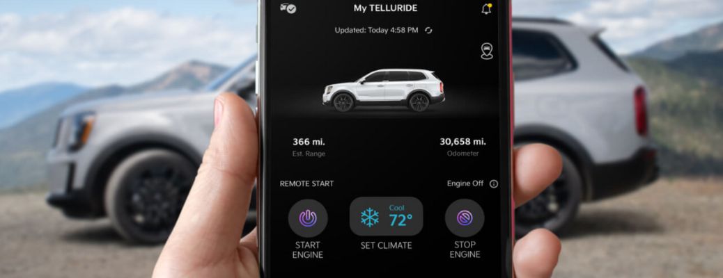 a hand holding a phone with Kia Connect on the screen