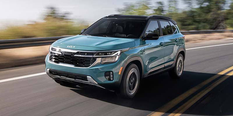  KIA SUV driving on a paved road, seen from a front three-quarter angle.